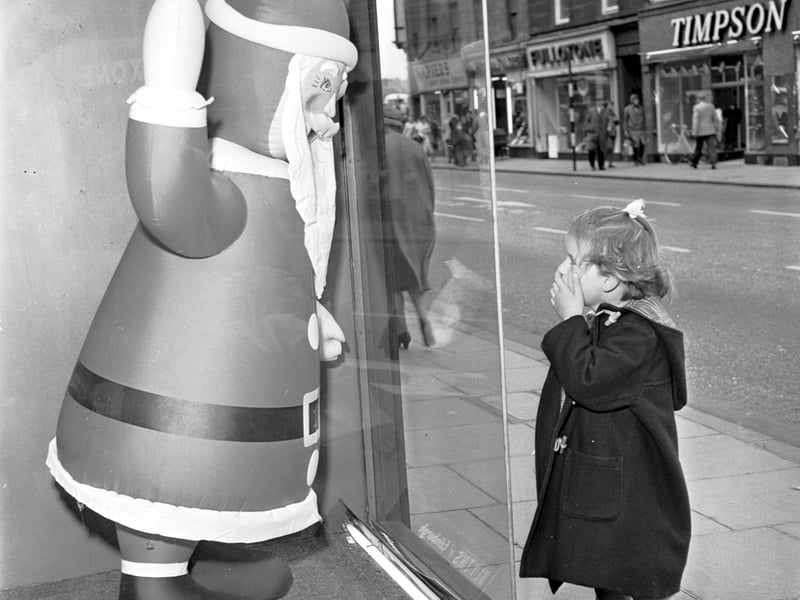 A little girl stops to admire the inflatable Santa Claus in the window of Blyth's department store, Earl Grey Street, Tollcross, in August 1964.
