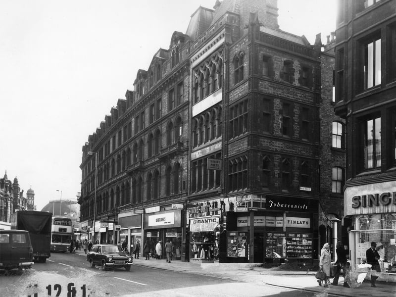 Boar Lane showing nos. 1 - 14, taken in the mid 1970s. No. 14 on the right is the Singer Sewing Machine Co. Next to this is the junction with White Horse Street, then no. 13 Finlay's tobacconist, no. 12 Stone-Dri weather wear and nos.10-11, temporary premises of Rawcliffe's clothiers. The next shop is vacant. Just visible at the end of the row is no.1 Alexandre Menswear. The Corn Exchange can be seen in the distance.