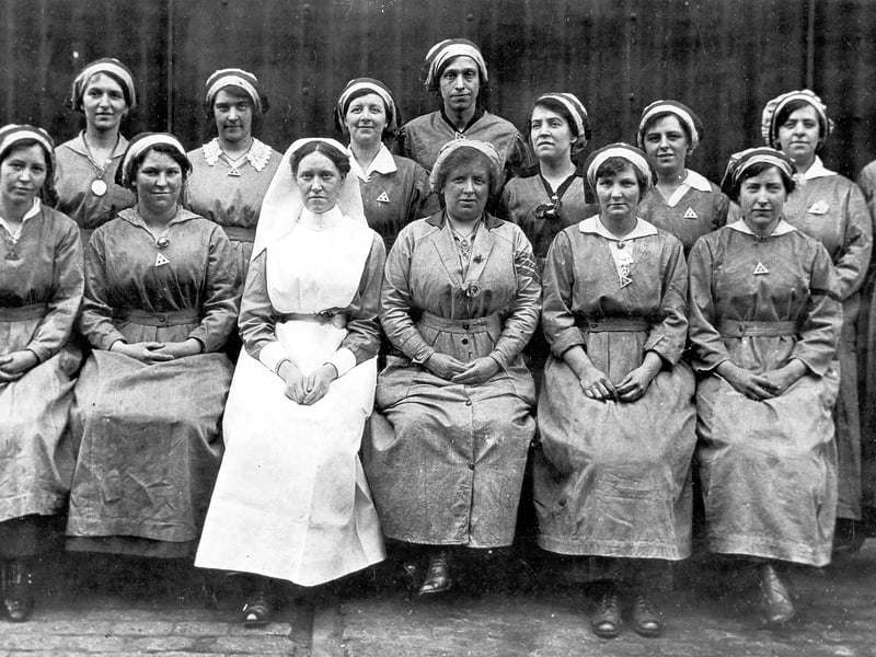 A group of munitions workers and a nurse. The women are wearing protective clothing, munition work was dirty and dangerous.