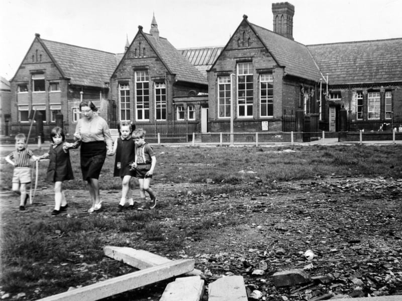 June Brelsford, headteacher of Whingate Road Primary School, Leeds, walks across the children's playground with pupils Simon Allan, Sally Nelson, Carolyn Dawson and Philip Snelson, all aged five, in May 1970