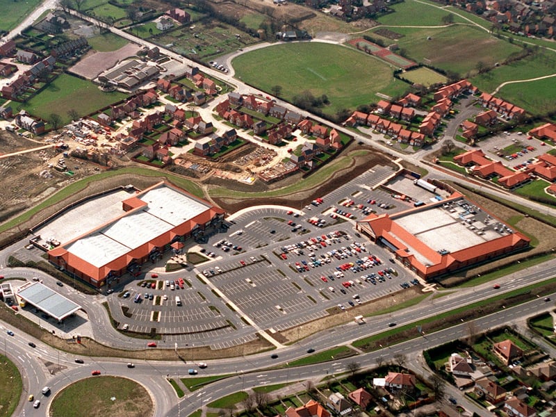 A bird's eye view of Colton retail park alongside the A63 with a block of mixed outlets on left and Sainsbury's on right and the green oasis of Colton Cricket Club at the top of School Lane. Pictured in April 1996.