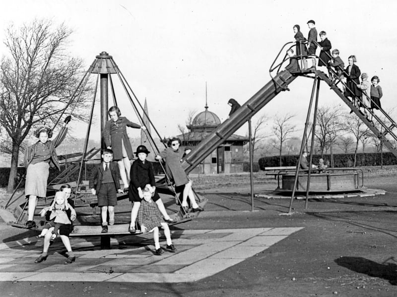 This photo from November 1945 shows children playing on swings and roundabouts in Woodhouse Moor. A slide is also visible with children queing up to play on it. A church can be seen in the background as can the shelter.