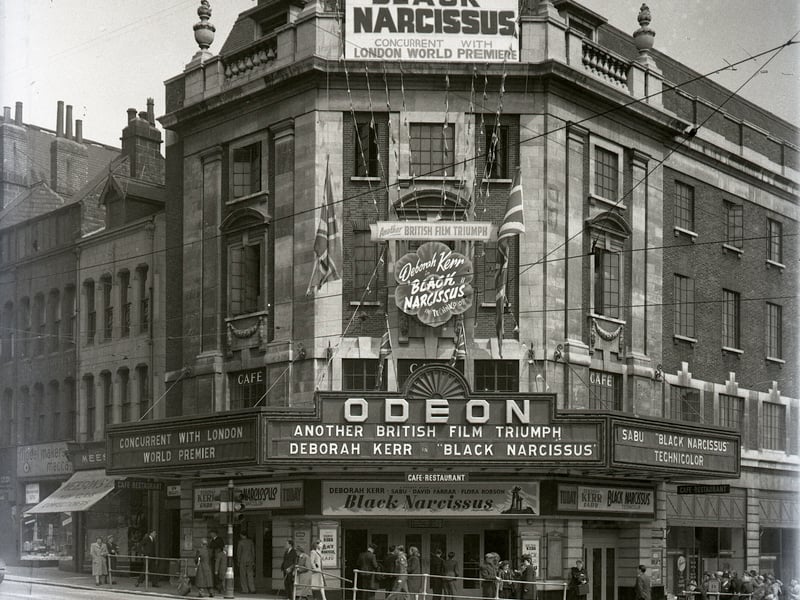 Odeon cinema & cafe-restaurant on The Headrow. It is showing 'Black Narcissus' film in Technicolor, 'Concurrent with London World Premiere' featuring Deborah Kerr and Sabu. Next door are Mecca Models and Meesons High Class Confectioners.