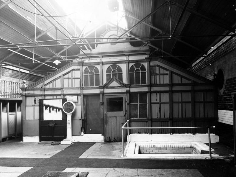The state of the interior of Union Street baths and washhouse on Cookridge Street in September 1947. A large building contains a smaller wooden one. In front is a large mirror, a set of upright scales and a sunken tiled bath. A sign above the scales warns customers of the consequences of 'indecent behaviour'