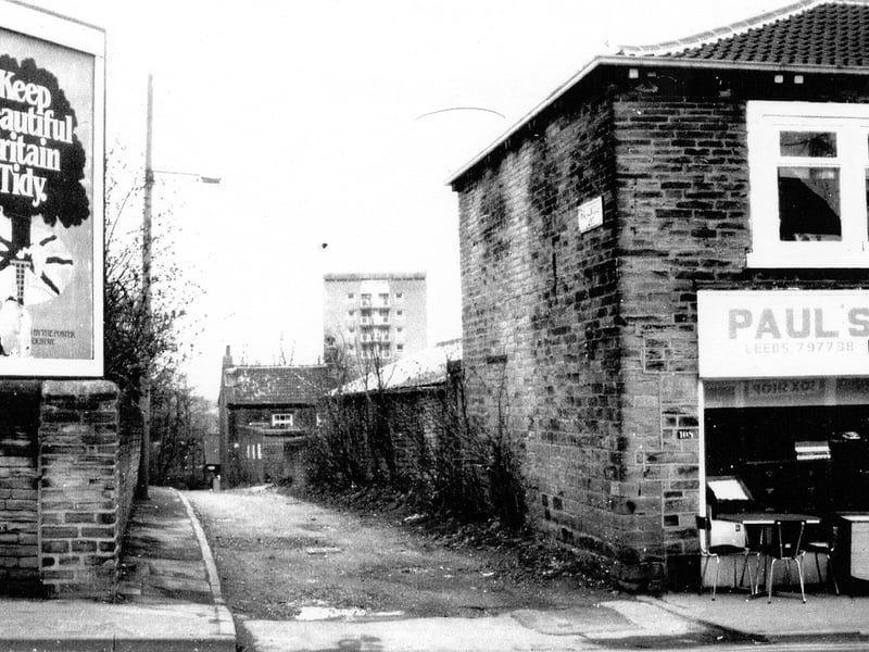 A view looking down Hollywell Lane from Armley Town Street near Moor Top circa 1970s. To the right on Town Street is Paul's New and Used Furniture shop. To the left an advertising poster states 'Keep Beautiful Britain Tidy'
