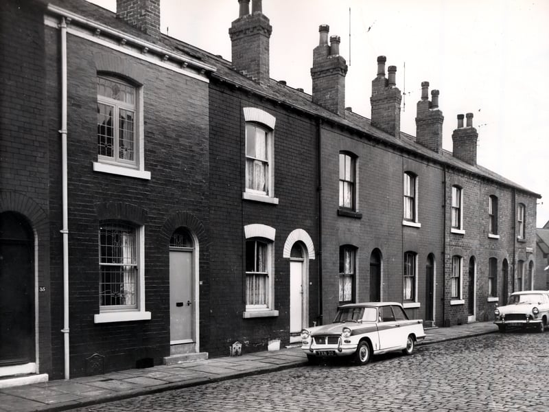 A view of through terraced properties in Northcote Terrace in November 1965. They open directly onto the pavement at this side and have yards and outside toilets at the rear. The street is paved in stone setts, typical of many of the streets in Leeds at this time.