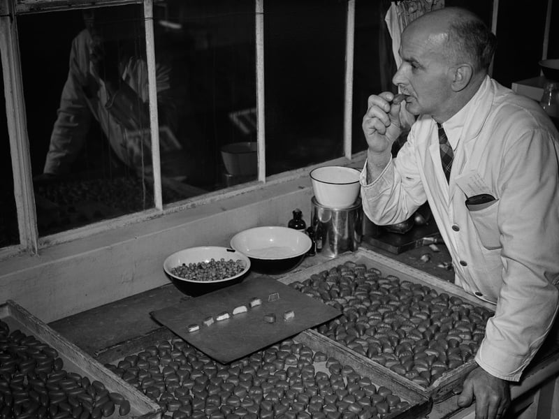 A man tastes chocolates laid out on a tray in front of him at the Nestle factory, Hayes, Middlesex, in November 1953