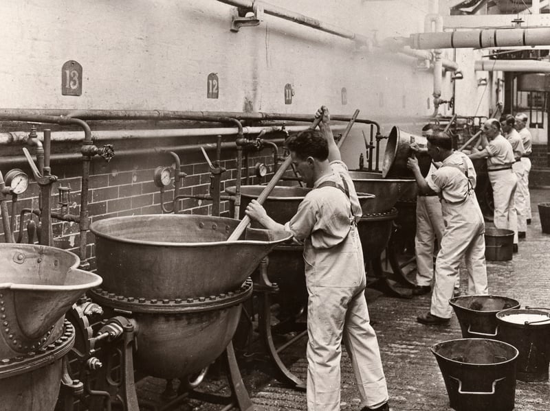 Men in dungarees stir boiling pans in the gum department of the Rowntree factory, York, in 1925