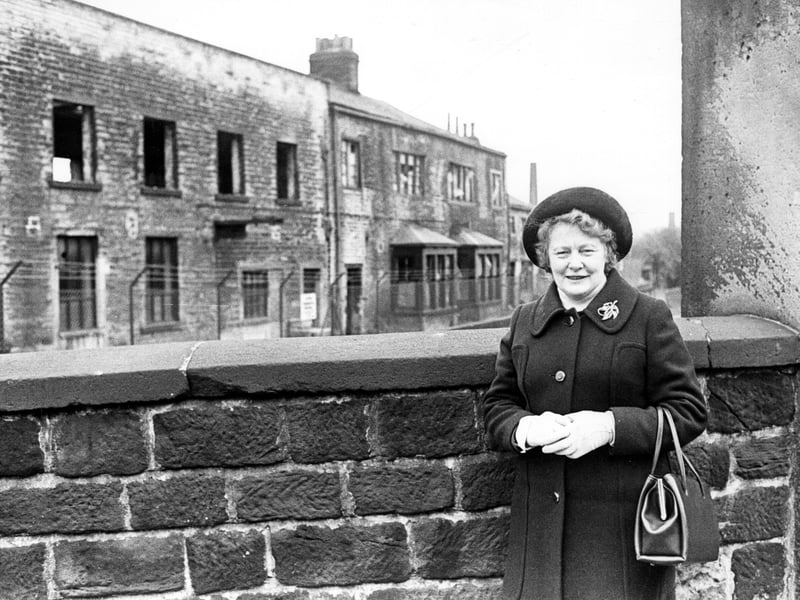 A view of cottages at Armley Mills circa 1970s with a former resident of the cottages in the foreground. The bay windows seen in the photograph were removed in the 1970s. The mill closed as a business in 1969 and was bought by Leeds City Council. It opened in 1982 as Leeds Industrial Museum.