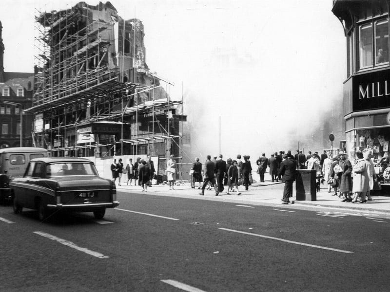Boar Lane showing the demolition of Royal Exchange Buildings taking place in May 1964. Several people have stopped to watch.