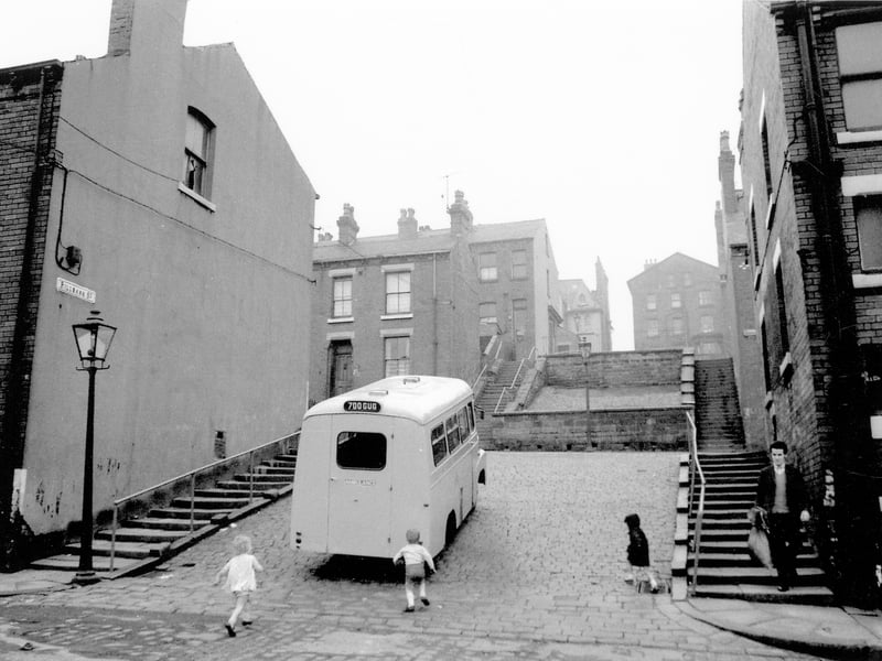 Rillbank Street taken from Westfield Crescent. A series of steps with hand-rails climb up either side to Rosebank Road. The two large properties seen in the background are the rear of large terraces, numbers 181 and 179 Belle Vue Road. Small children run towards the ambulance parked in Rillbank Street.
