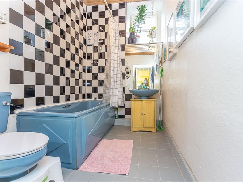 The coloured bathroom suite and electric shower over the bath.