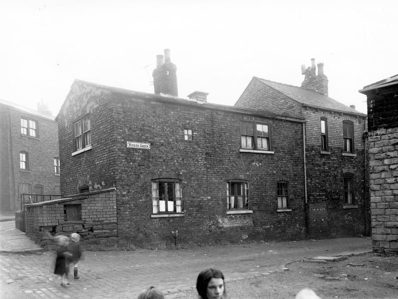 The rear of through by light terraced houses numbers 48 to 50 Theaker Lane. Children are visible stood in the cobbled street in the foreground. Pictured in November 1957.