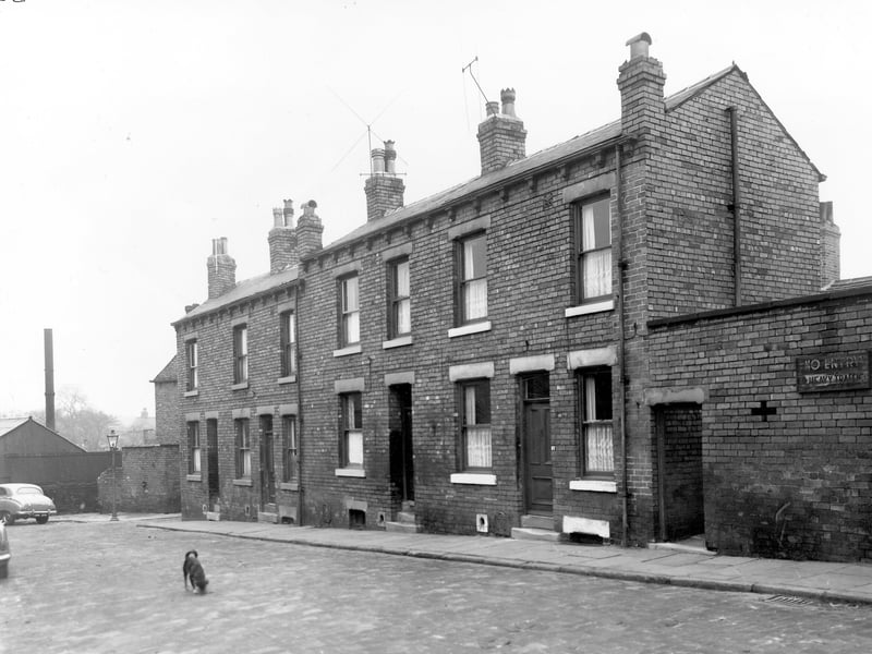 A row of four back-to-back terraced houses on a cobled street. On the far left is the entrance to Eyres Place and on the right is a shared outside toilet block where a sig reads 'No Entry' to heavy traffic. Pictured in November 1957.