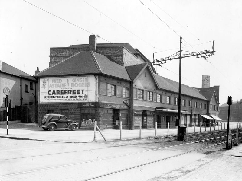 Clock Buildings, a parade of shops in front of the cinema in Roundhay Road. The junction with Copgrove Road is at the left edge. On the left, Clock Provision Stores can be seen, and to the right is C.H. and F. Lax builders with houses for sale or to rent. Pictured in May 1939.