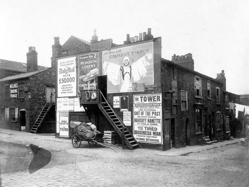 Virginia Cross Street was at the junction of Harewood Street and Nelson Street, which is on the right. To the laft, forge belonging to William Milnes, shoeing smith, with outside stairs to upper floor. In the centre, wooden stairs lead to doorway, premises of J.Rogers a saddlery goods dealer. Pictured in July 1928.