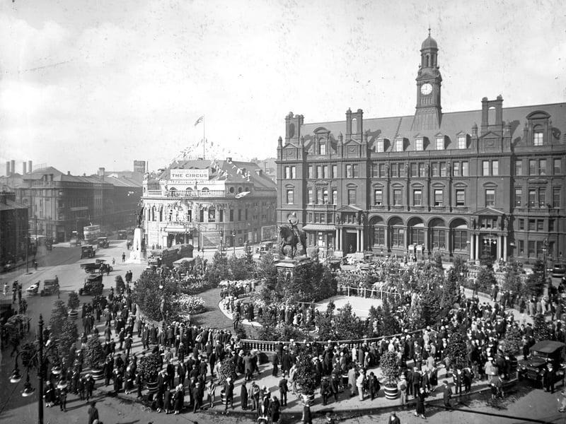 A view looks across City Square towards Wellington Street, the Majestic Cinema and the General Post Office in September 1928. The Square is thronged with people taking part in Civic Week celebrations and has been decorated with lawns, flowers, and small trees.