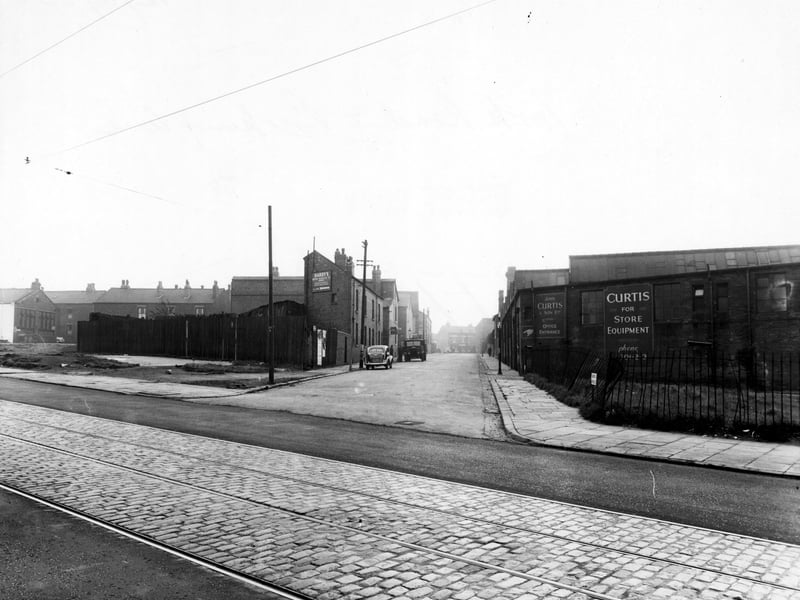 A view from October 1950 looking down Berking Avenue from York Road, with the premises of John Curtis & Son Ltd, store equipment, on the right and Hardy's Motor Radiator Company on the left. York Road has tram tracks and overhead power lines.