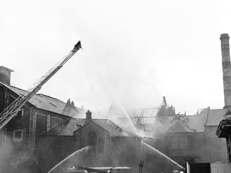 On lookers watch as firemen fight the flames at  Murrays Brewery, in Craigmillar, in March 1966.