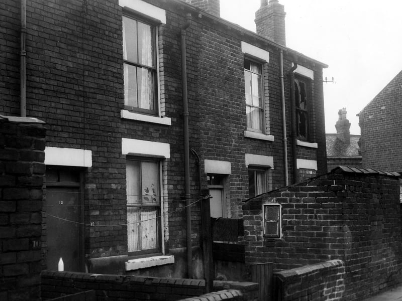 Back Hanover View in November 1969. The photo shows the rear entrances and yards of through terraced houses numbers 12 to 16 Hanover Grove. Each yard has an outside toilet block. A milk bottle awaits collection from the yard wall of number 12 on the left. The door of number 16 on the right is bricked up and the upstairs window has been smashed.