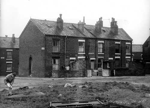 Hanover Avenue and Hanover Mount pictured in November 1969. The photo shows the rear entrances and yards of a row of through terraced houses numbers 2 to 8 Hanover Mount. Outside toilets, one shared between two homes are located in the yards. In the foreground is a grassed area where a man is visible on the left.