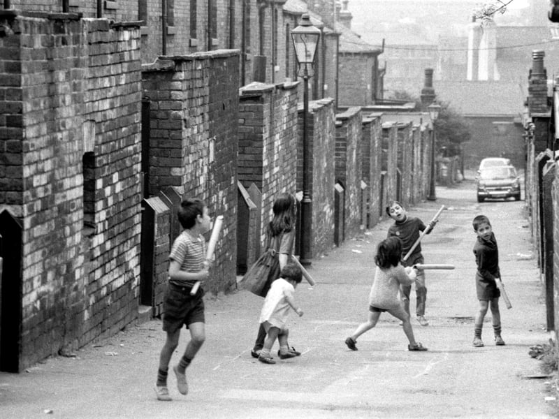 Rillbank Lane looking down towards Westfield Road, with Burley Road at the bottom. A group of girls and boys of varying ages play out in the street with what appear to be plastic pipes or cardboard tubing.
