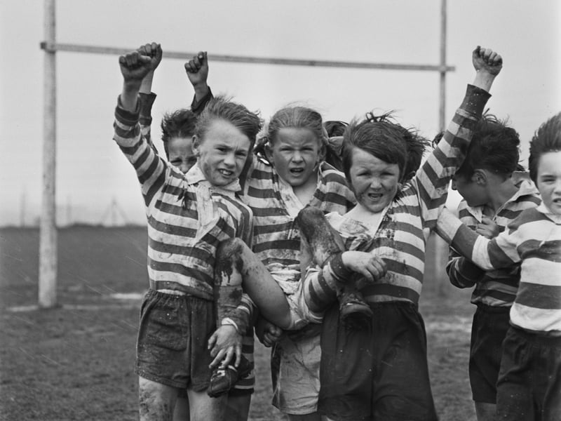 Schoolgirl Yvonne Davis and her teammates celebrate with their arms raised during a school rugby league match at Clapgate Primary School, Leeds, in April 1972