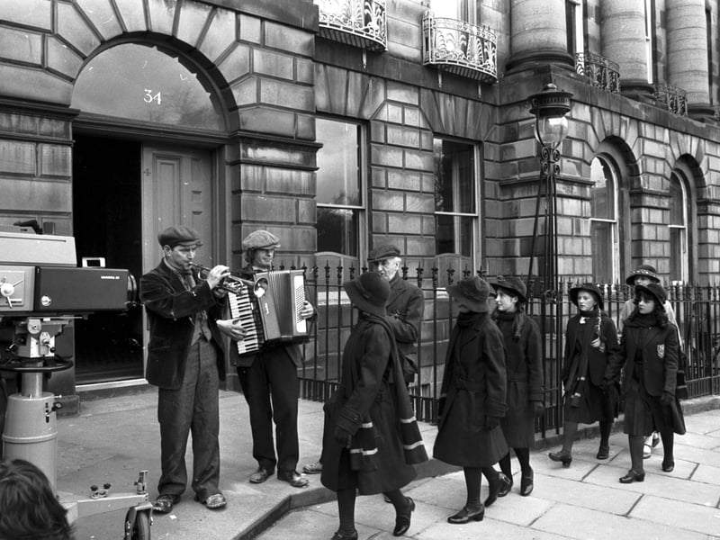 STV filming their TV series 'The Prime of Miss Jean Brodie', on Moray Place, Edinburgh, in April 1977. The camera rolls as Geraldine McEwan and her 'gerls' walk towards a three-piece street band.