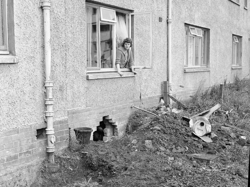 Rina Crockett watches workmen trying to find the source of the flooding in her home at Muirhouse Park in September 1964.