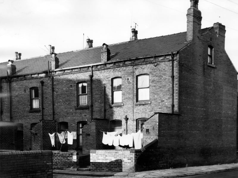 The rear of through red brick terraced houses in Freestone Place seen from the junction with Disraeli Terrace. Houses front onto Freestone Street and are numbered from left to right, 10 to 14. Washing lines are strung between brick built toilets across small walled yards. Pictured in November 1965.