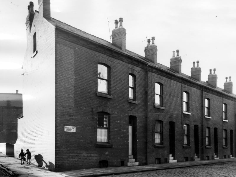 Red brick through terraced properties in Freestone Street seen from the junction with Disraeli Terrace. Houses number from left to right, 14 to 6, and have small yards at the rear. Two small boys can be seen walking on Disraeli Terrace in the direction of Lady Pit Lane. Pictured in November 1965.