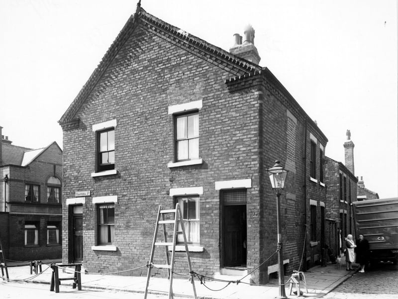 Chantrell Street in June 1950. The houses have been cornered off by rope and various objects such as ladders and saw horses. Two women are stood by a van with a dog and are looking at the camera. The New Regent Hotel is visible to the left of the photo.