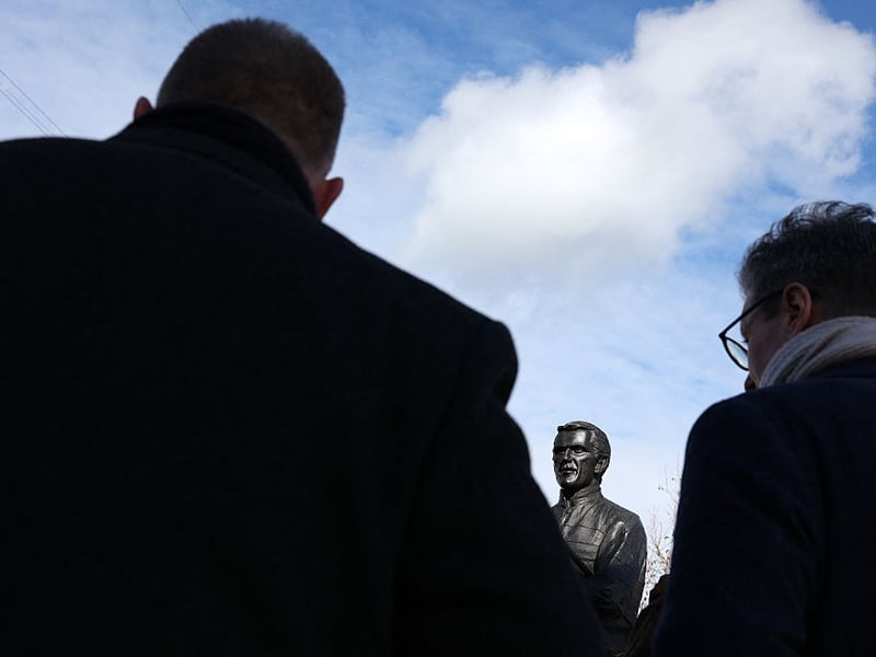 Racegoers crowd around the statue of former champion jockey AP McCoy.