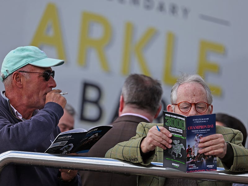 Racegoers study the form guide ahead of racing on the first day of the Cheltenham Festival.