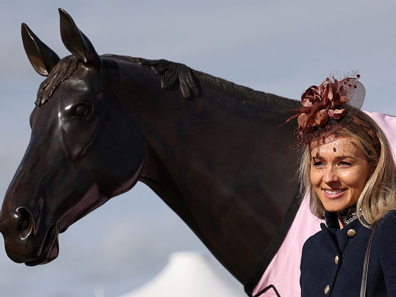 A racegoer poses for a photograph with a statue of Best Mate.