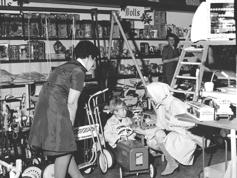 A little boy tries out the pedal car in the toy department of Patrick Thomson's store, Edinburgh, before Christmas 1968