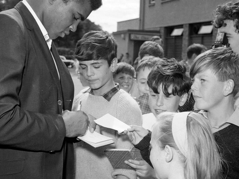 Boxer Muhammad Ali (formerly Cassius Clay) signs autographs for children on his arrival in Glasgow in 1965