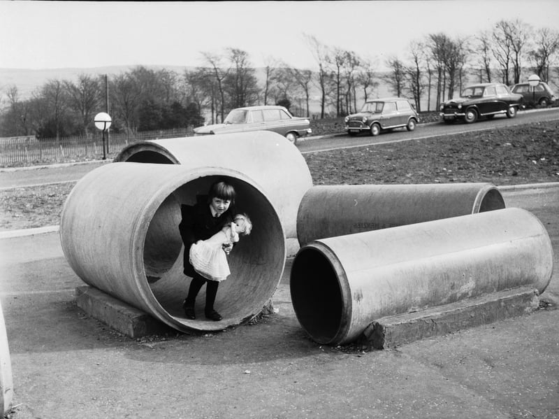 A child at a Glasgow primary school playing with her doll in drainage pipes in April 1966