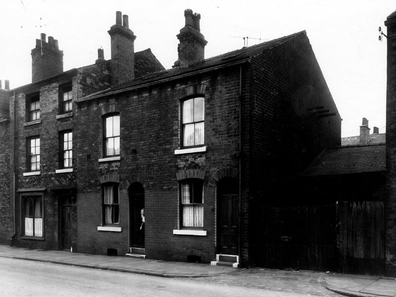 A man is pictured peering from the doorway of a house on  Wordsworth Street in November 1959.