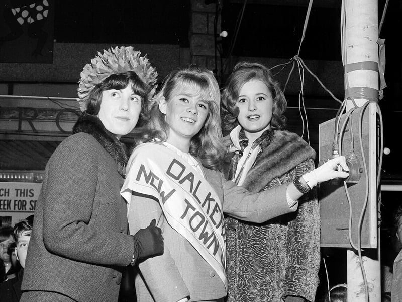 Dalkeith's New Town Girl, 18-year-old Joan Hepburn, switches on the town Christmas lights watched by runners-up Ruth Wysick and Teresa O'Brien in December 1964.