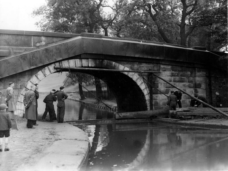 Redcote Bridge over the Leeds Liverpool Canal in September 1942. A demonstration of fixing a canal 'boom' by workmen in boiler suits is in progress, watched by two men and two children to the left.