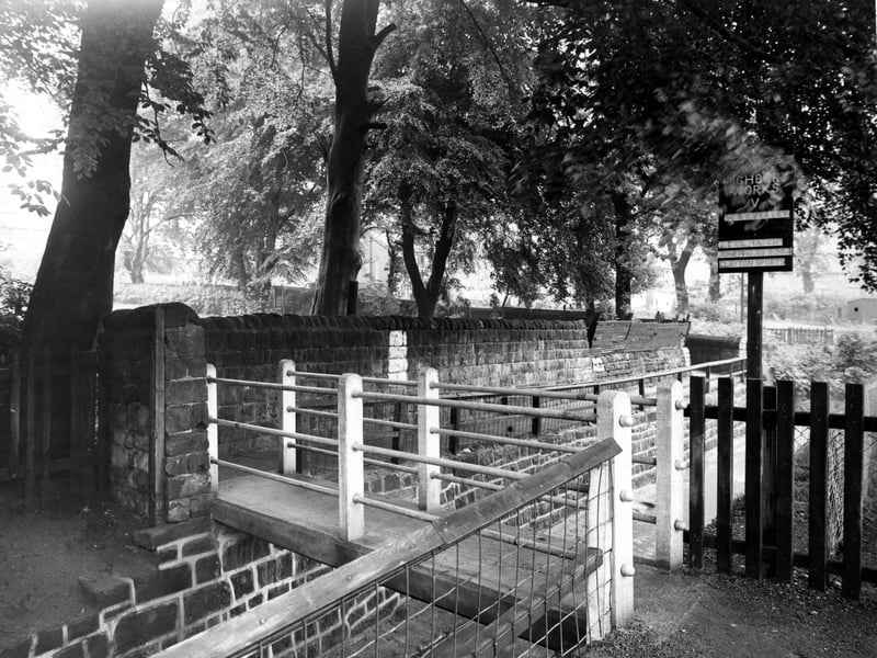 Bridge number 78 over Meanwood Beck pictured in June 1948. The concrete footbridge crosses the beck as it flows through a stone channel between Highbury Cricket Club's pitch on the right, and Meanwood Park on the left (over the stone wall). A sign advertising a match between Highbury Works C.C. and Calverley is visible.