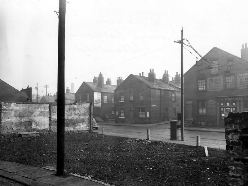 The junction of Elland Road with Rhodes Street. Number 39 Elland Road is the premises of 'S. Whitaker, Corn Merchant'. There are adverts visible for 'Pulbis Dog Food', 'Melox Meals Build Bonnie Puppies', and 'Dairy Milk'. Pictured in December 1952.