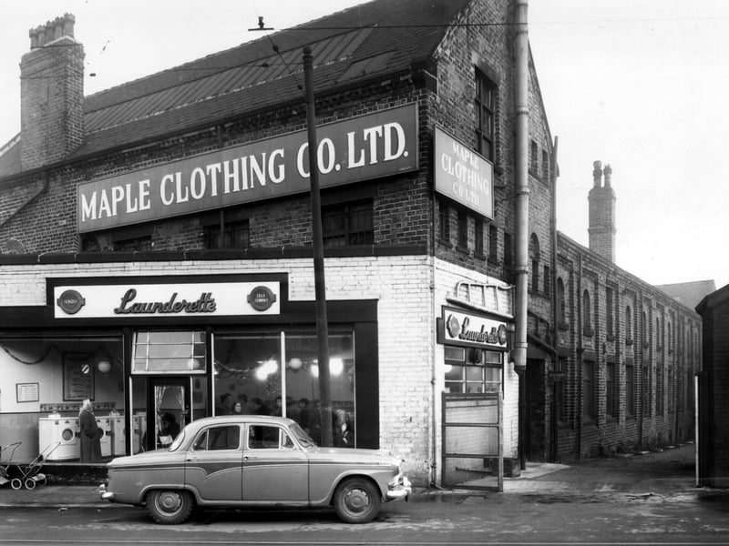 A car parked outside a Bendix, Self Service Laundrette on Dewsbury Road in December 1958. Christmas decorations are visible hanging from the ceiling. Above and behind the laundrette is the Maple Clothing Co Ltd, blouse factory. On the right is Admiral Street.