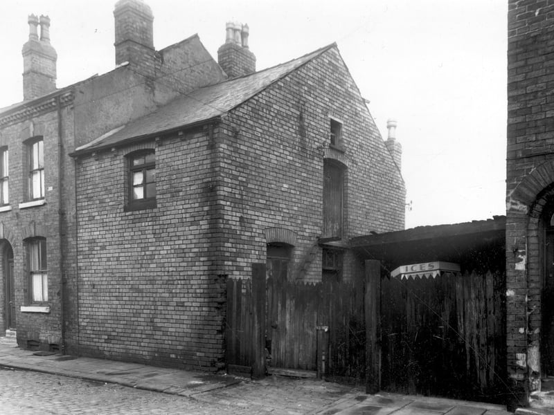 On the left is number 15 Dow Place with number 21 on the right, between these two houses there is a non residential building on the left and a yard on the right. Behind the high wall of the yard can be seen the top of an ice cream van displaying the sign 'ices'. Pictured in December 1958.