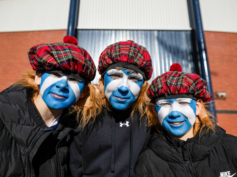 Three young Scotland fans with saltires painted on their faces.