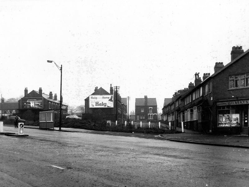 Looking north west across Stanningley Road along South End Grove. Advertisement for Haig beer on the gable end of house. Keep left signs, a bus stop, a cyclist, a lamp post and Gilbert's grocers visible. Pictured in November 1968.