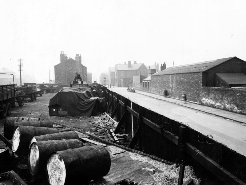 The yard of Archbolds Haulage at the corner of Leathley Road and Cross Myrtle Street surrounded by a high wooden fence. In the yard are stacks of oil drums and parked lorries. Pictured in April 1947.