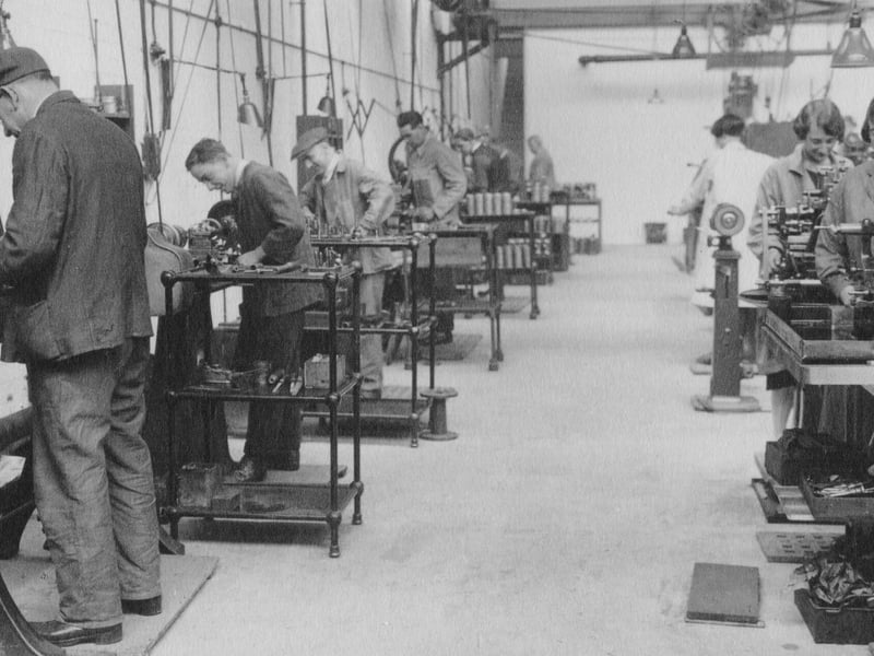 Employees engaged in manufacturing work at a bay in the machine shop circa 1927.