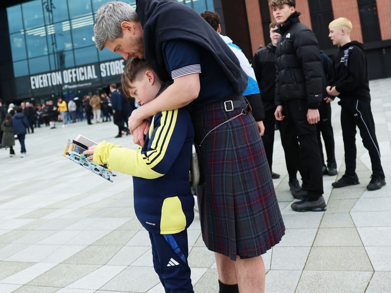 Scotland fans read the matchday programme outside the stadium.